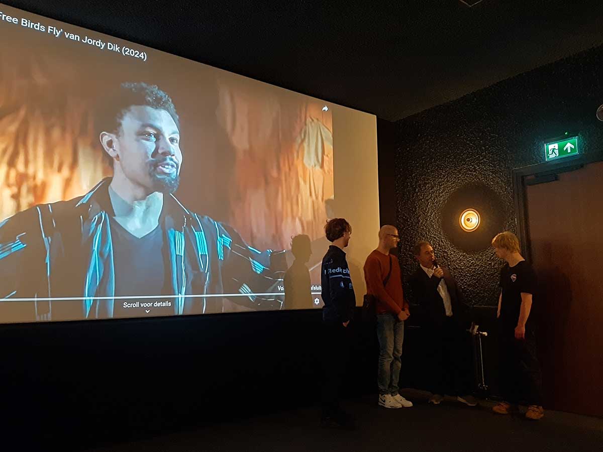 Foto van Wouter Schelvis die op het podium een interview afneemt van de mannen van Tiuri.